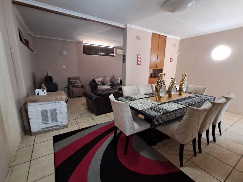 Open-plan living and dining area featuring tiled flooring and built-in cabinetry, offering a functional layout with potential for modern updates.