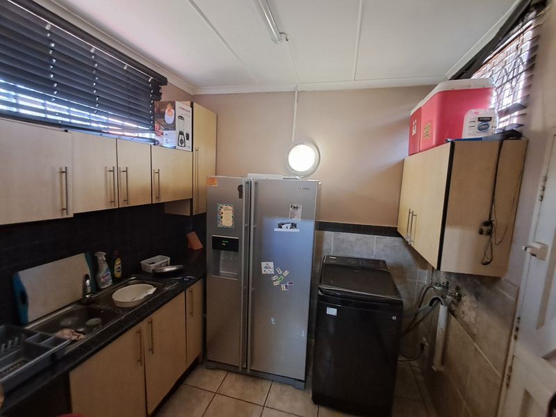 Functional laundry area featuring built-in cabinetry, tiled splashbacks, and dedicated plumbing connections for appliances.