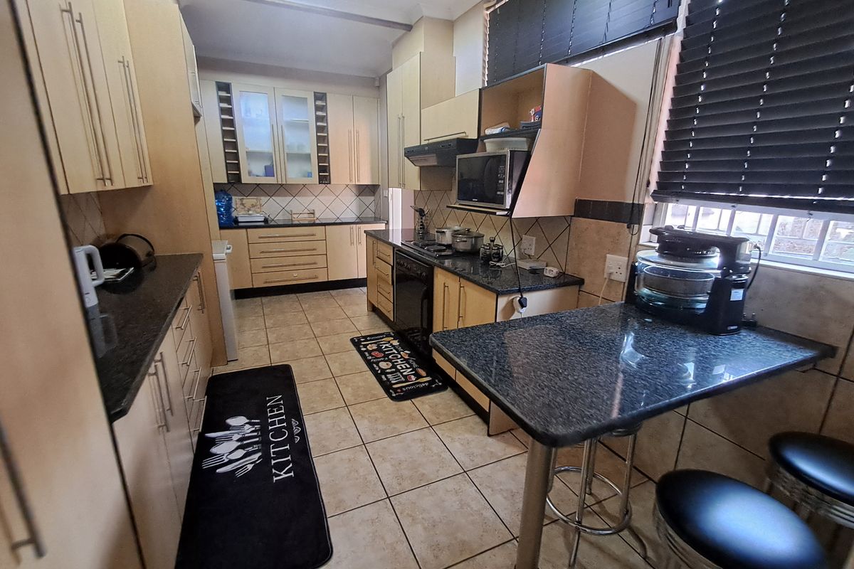 A functional kitchen featuring granite countertops, built-in cabinetry, a breakfast bar, and tiled flooring, offering a practical layout for daily meal preparation.