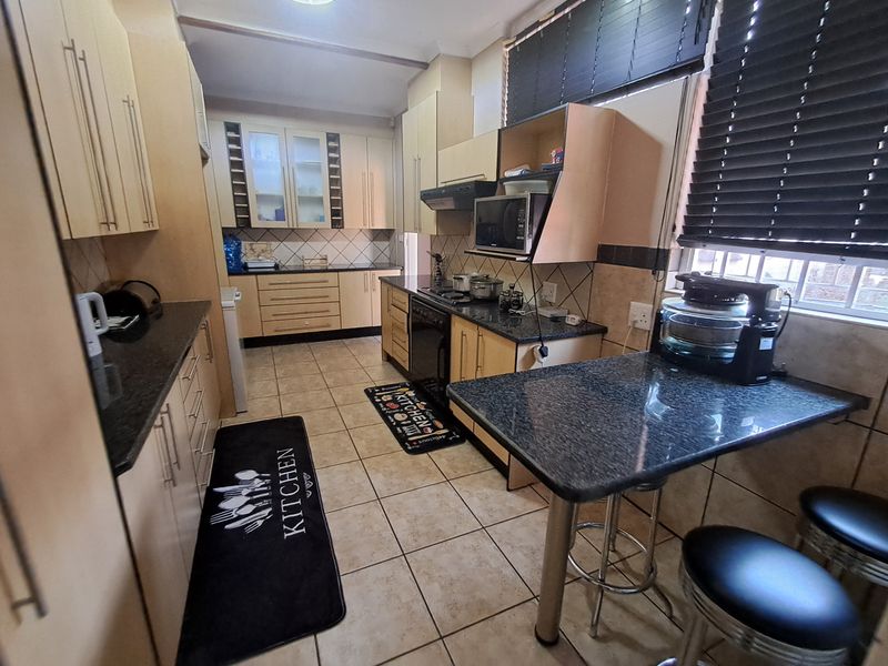A functional kitchen featuring granite countertops, built-in cabinetry, a breakfast bar, and tiled flooring, offering a practical layout for daily meal preparation.