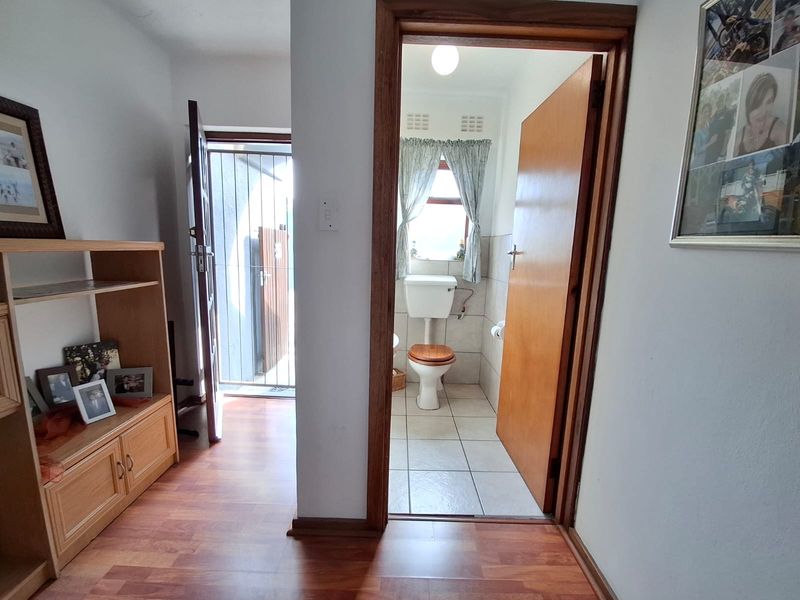 A view from a living area looking into a small bathroom with tiled floors and a toilet, adjacent to an exterior security door.