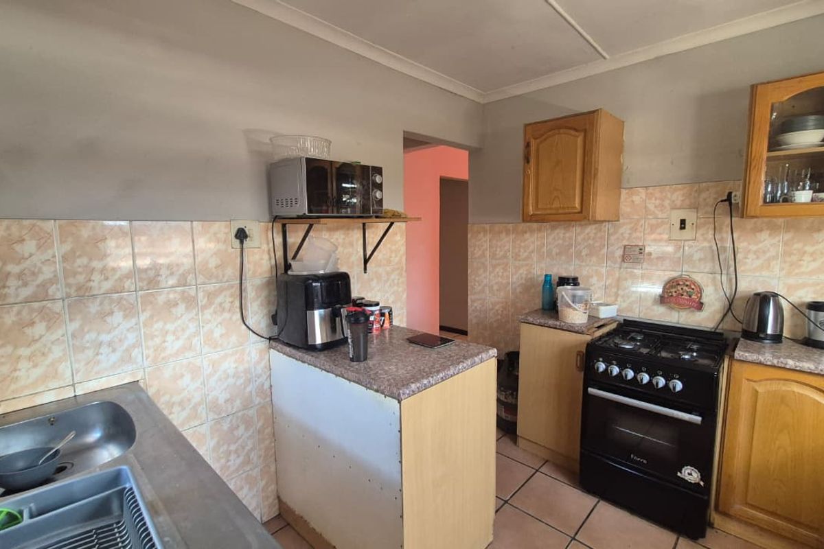 A functional kitchen featuring dated cabinetry, tiled backsplash, and a gas stove, offering potential for modernization and aesthetic improvement.