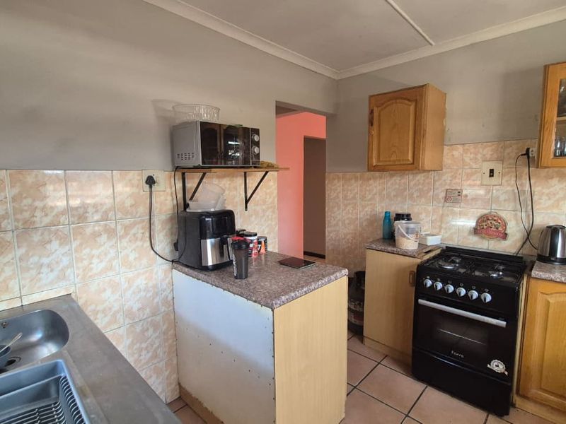 A functional kitchen featuring dated cabinetry, tiled backsplash, and a gas stove, offering potential for modernization and aesthetic improvement.
