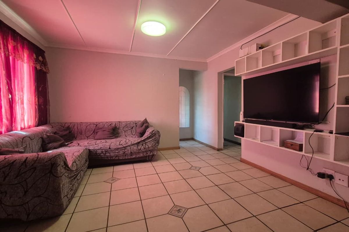 A living room featuring tiled flooring and a large built-in shelving unit, providing functional storage and display space.
