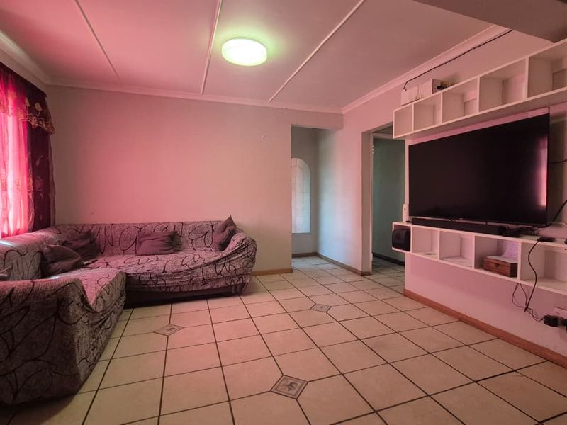 A living room featuring tiled flooring and a large built-in shelving unit, providing functional storage and display space.