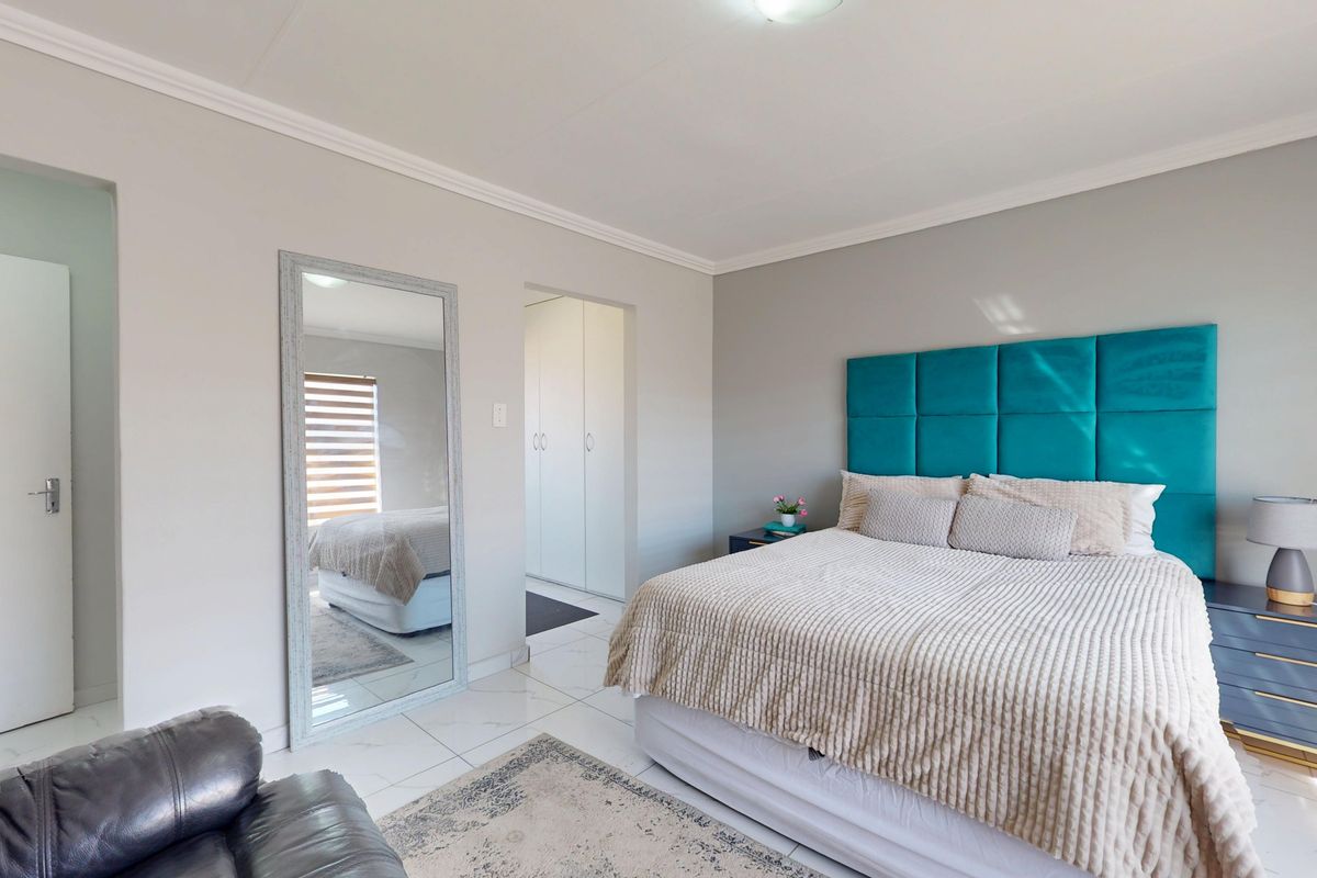 A well-maintained bedroom featuring tiled flooring, built-in cupboards, and decorative cornice detailing, offering a clean and neutral living space.
