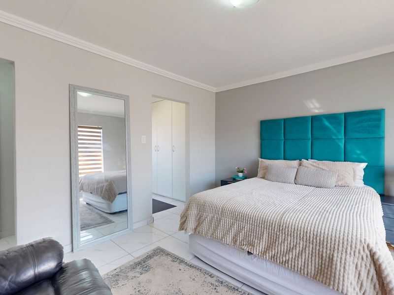 A well-maintained bedroom featuring tiled flooring, built-in cupboards, and decorative cornice detailing, offering a clean and neutral living space.