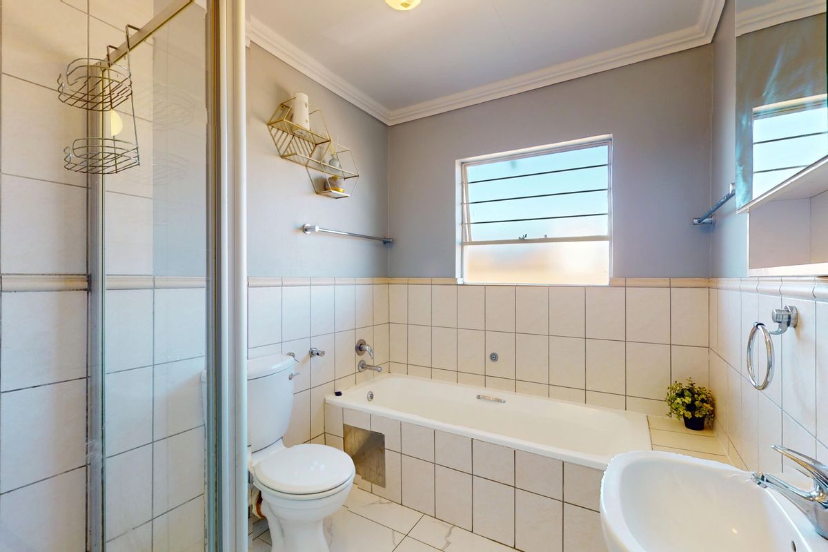 A clean and functional bathroom featuring a separate shower enclosure, bathtub, toilet, and washbasin with neutral wall and floor tiling.