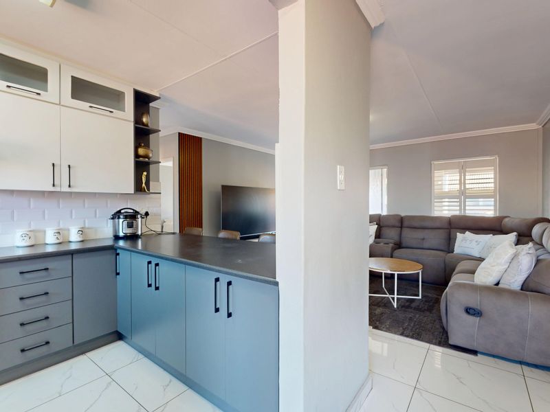 Modern open-plan kitchen and living area featuring sleek cabinetry, a subway tile backsplash, built-in appliances, and polished tiled flooring throughout.