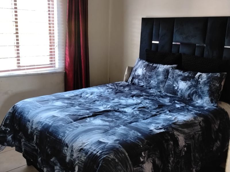 A standard bedroom featuring tiled flooring and a window with blinds, providing a functional space for rest.