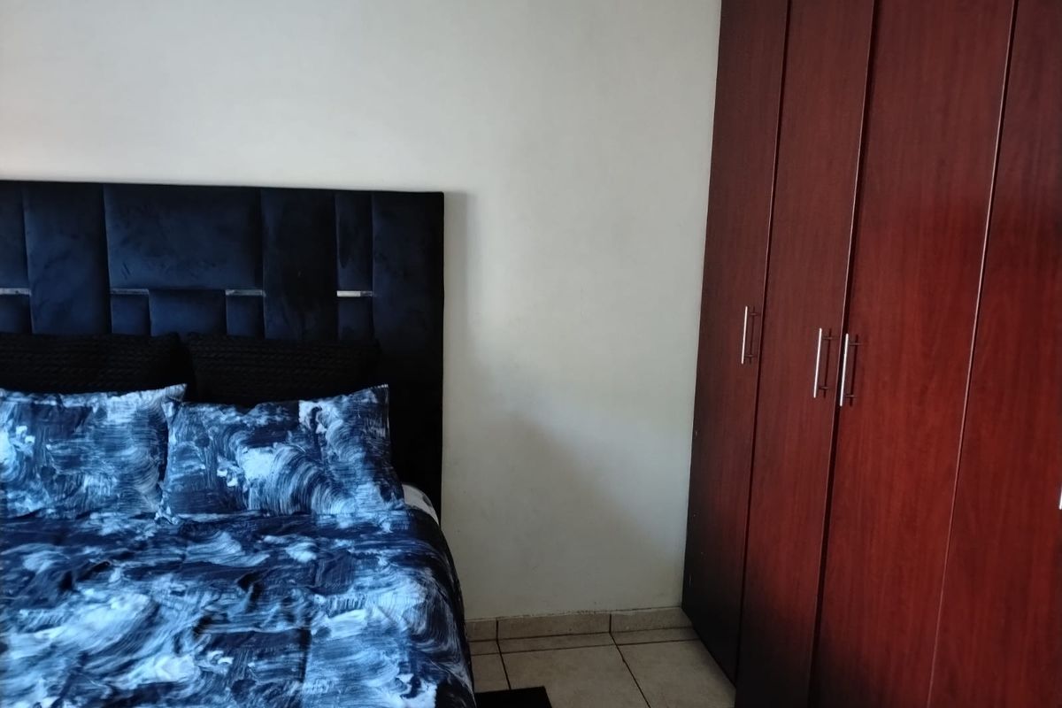 A bedroom featuring a built-in wooden wardrobe and tiled flooring.