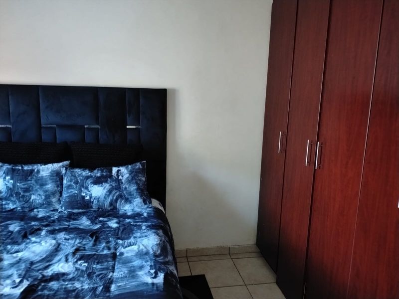 A bedroom featuring a built-in wooden wardrobe and tiled flooring.