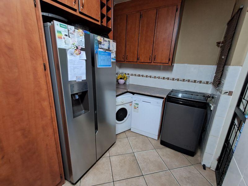 A functional laundry area featuring built-in wooden cabinetry, laminate countertops, and tiled flooring, providing practical storage and workspace for household utility tasks.