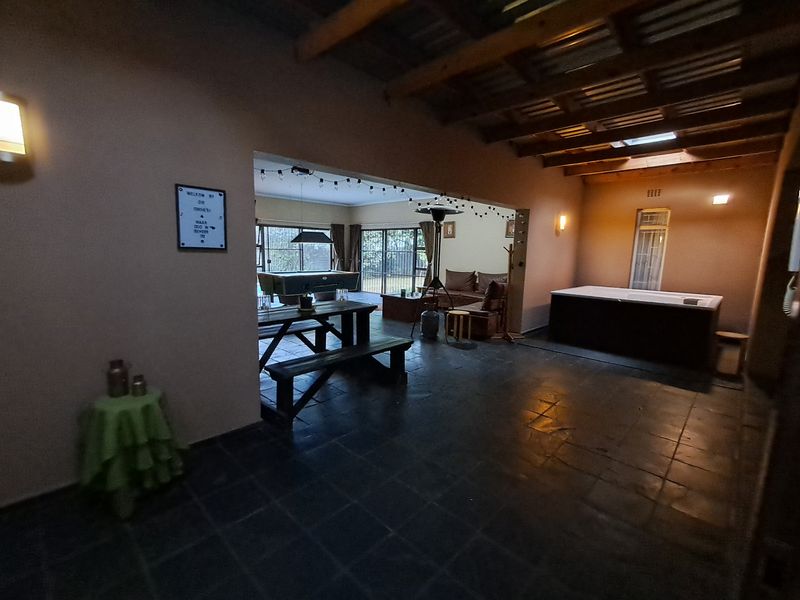 Spacious covered patio area featuring slate flooring, exposed timber beams, a skylight, and a built-in hot tub, seamlessly connecting to the living space.