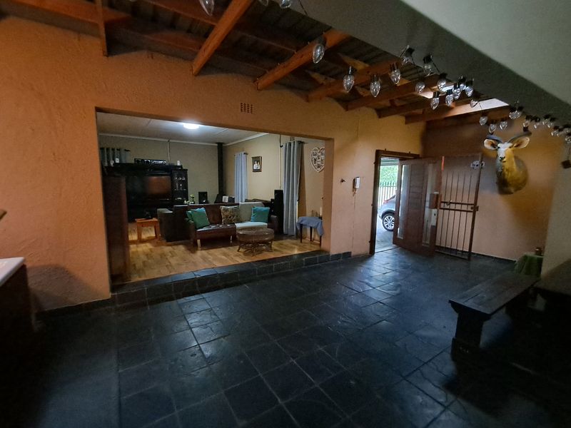 A covered patio area featuring exposed timber beams and slate flooring, providing a transition space between the outdoor area and the interior living room.