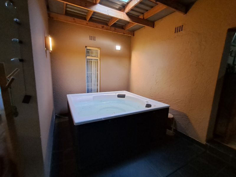 An indoor spa area featuring a built-in jacuzzi, exposed timber roof beams, and a skylight, creating a private relaxation space.