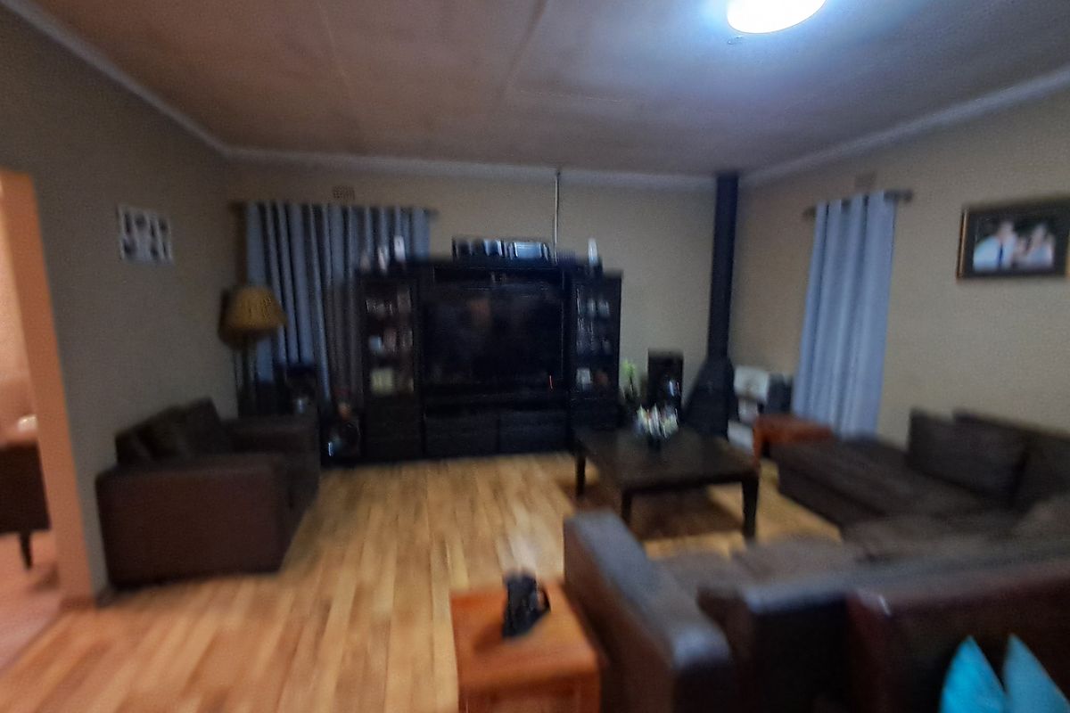 A living room featuring wood flooring and a freestanding fireplace, providing a functional space for relaxation.