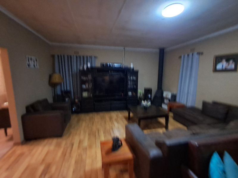 A living room featuring wood flooring and a freestanding fireplace, providing a functional space for relaxation.