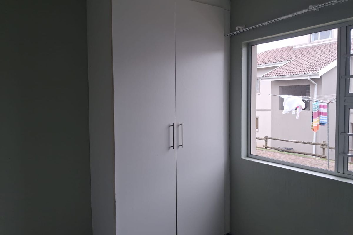 A clean, empty bedroom featuring a white built-in wardrobe and a window with security bars, offering a neutral space ready for personalization.
