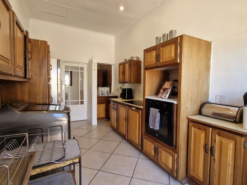 A functional kitchen featuring traditional wooden cabinetry, built-in oven, tiled backsplash, and tiled flooring, offering a classic layout with potential for modern updates.
