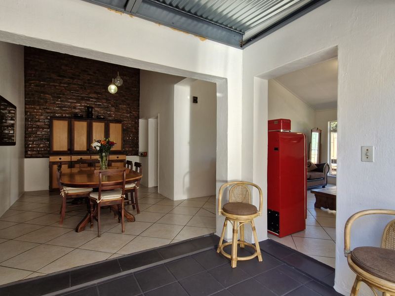 Open plan living and dining area featuring exposed brick walls, tiled flooring, and a corrugated metal ceiling.