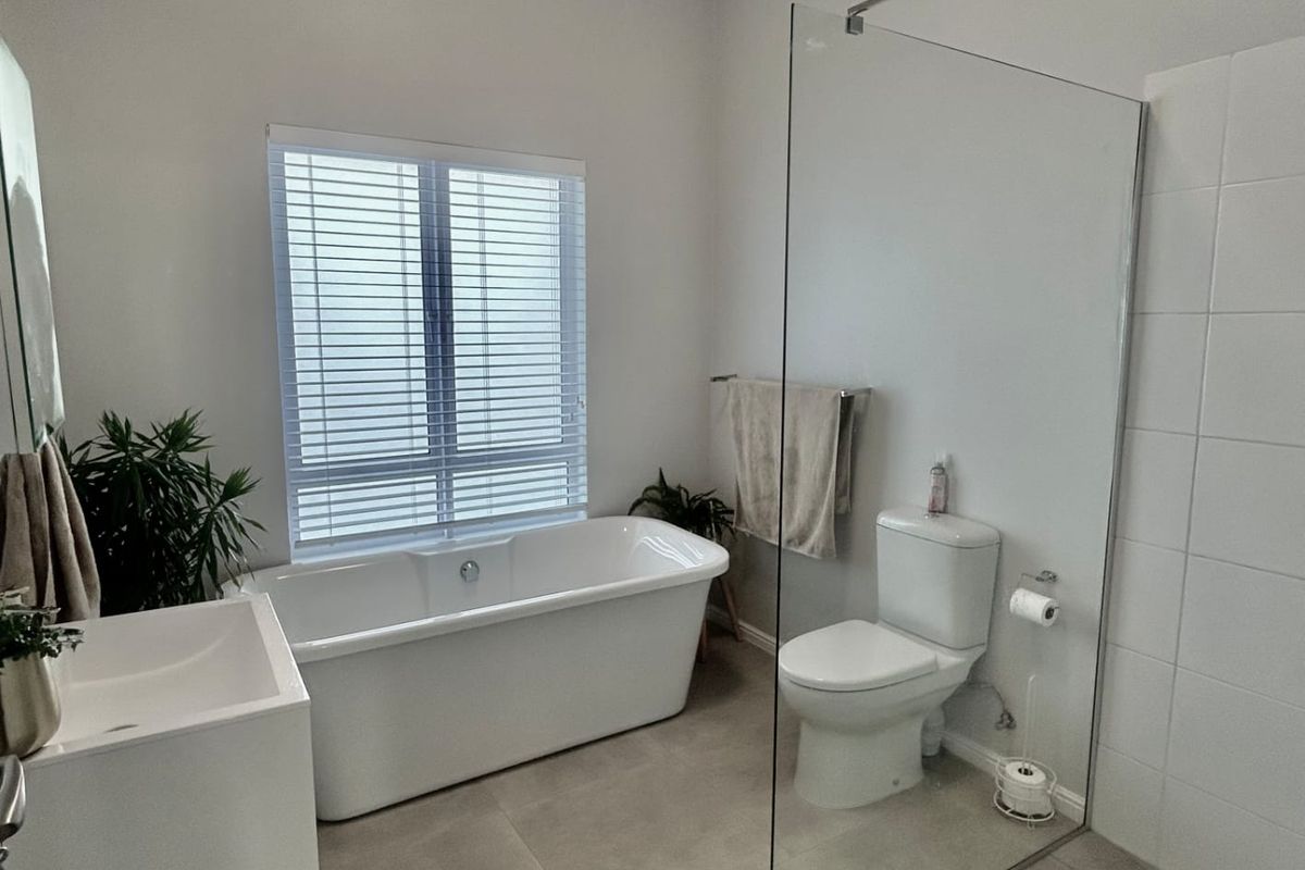 Modern bathroom featuring a freestanding bathtub, a spacious walk-in shower with a glass screen, and a wall-mounted vanity with neutral floor tiles.