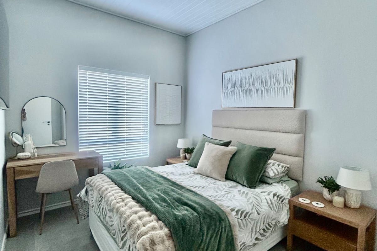 A well-maintained bedroom featuring neutral tiled flooring, a high tongue and groove ceiling, and fitted venetian blinds.