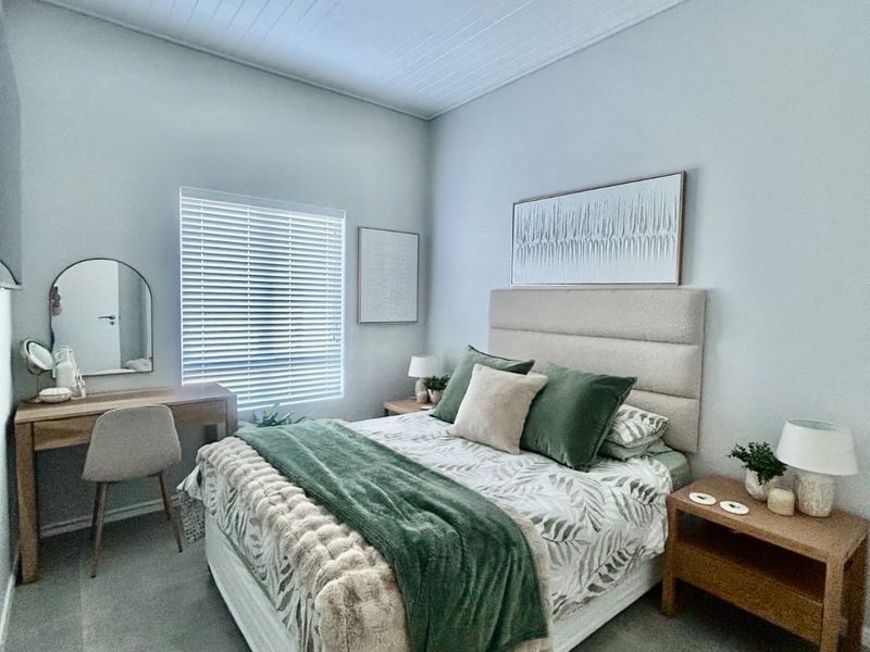 A well-maintained bedroom featuring neutral tiled flooring, a high tongue and groove ceiling, and fitted venetian blinds.
