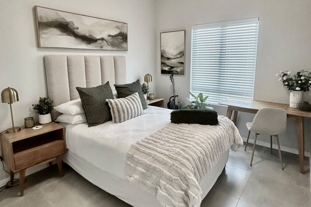 A well-maintained bedroom featuring neutral tiled flooring and venetian blinds, offering a clean and modern aesthetic.