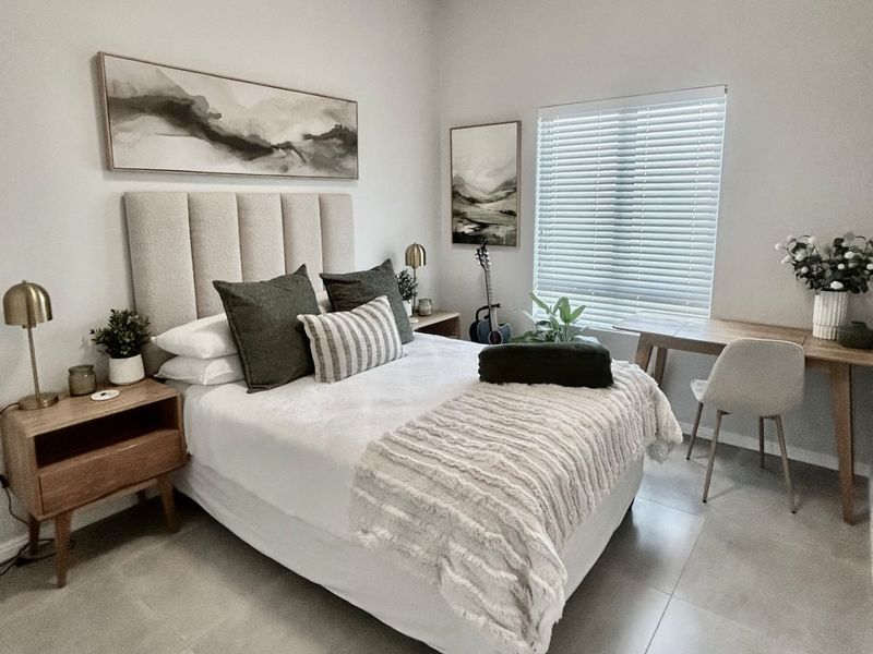 A well-maintained bedroom featuring neutral tiled flooring and venetian blinds, offering a clean and modern aesthetic.