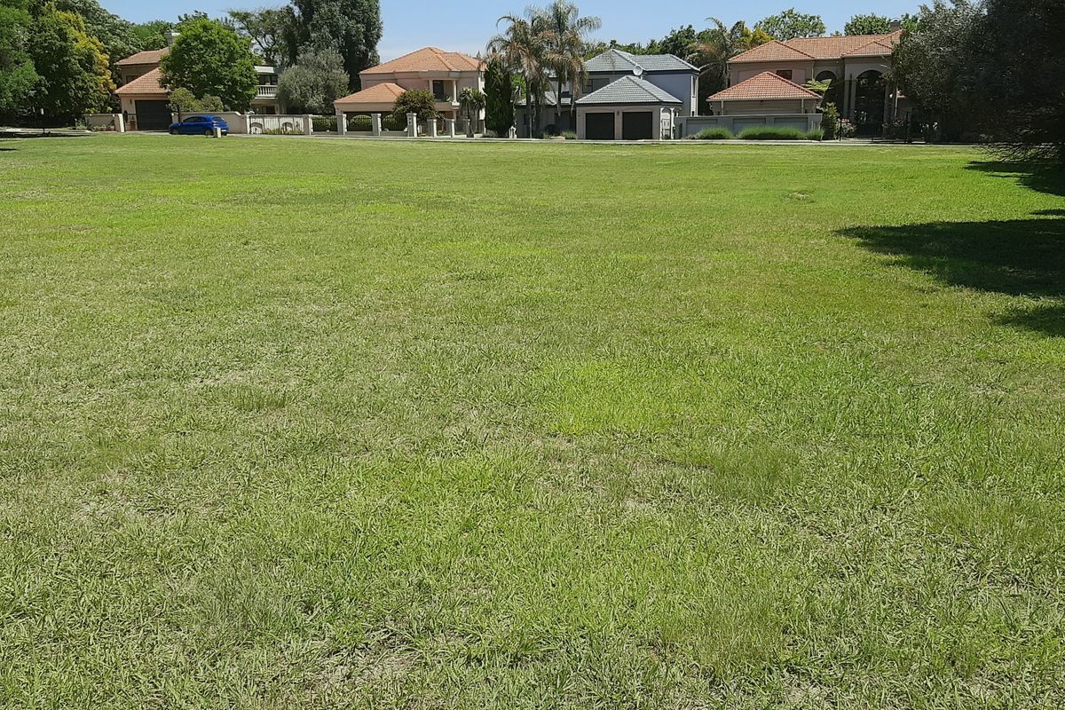 A spacious, level residential vacant land plot featuring well-maintained grass and mature trees, situated in an established neighborhood.