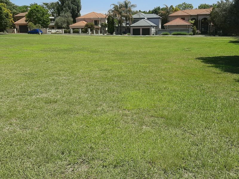 A spacious, level residential vacant land plot featuring well-maintained grass and mature trees, situated in an established neighborhood.
