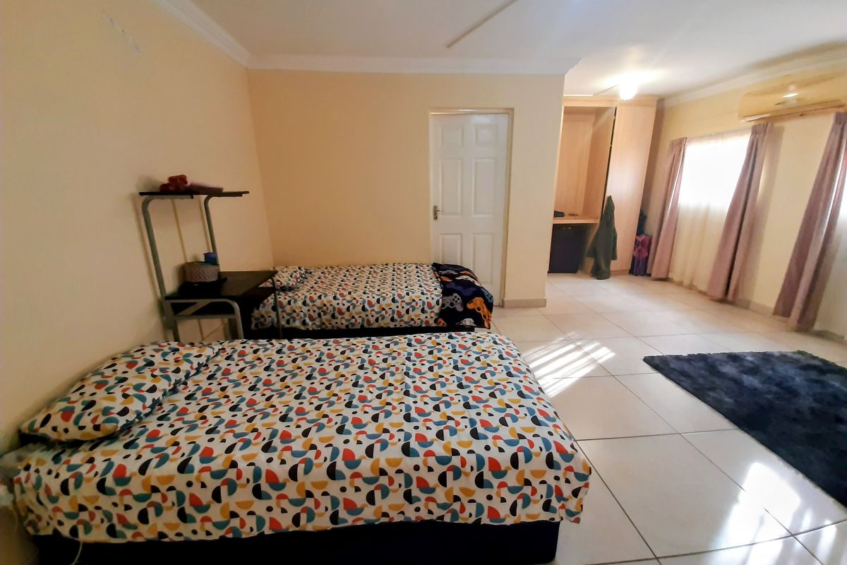 Spacious bedroom featuring tiled flooring, built-in wardrobe storage, and an integrated air conditioning unit.