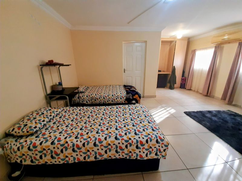 Spacious bedroom featuring tiled flooring, built-in wardrobe storage, and an integrated air conditioning unit.