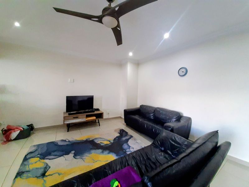 A living room featuring tiled flooring, recessed lighting, and a ceiling fan, providing a functional and neutral space for relaxation.
