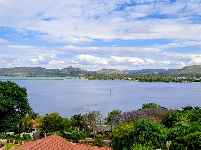 A scenic elevated view overlooking a large lake with surrounding hills and lush greenery.