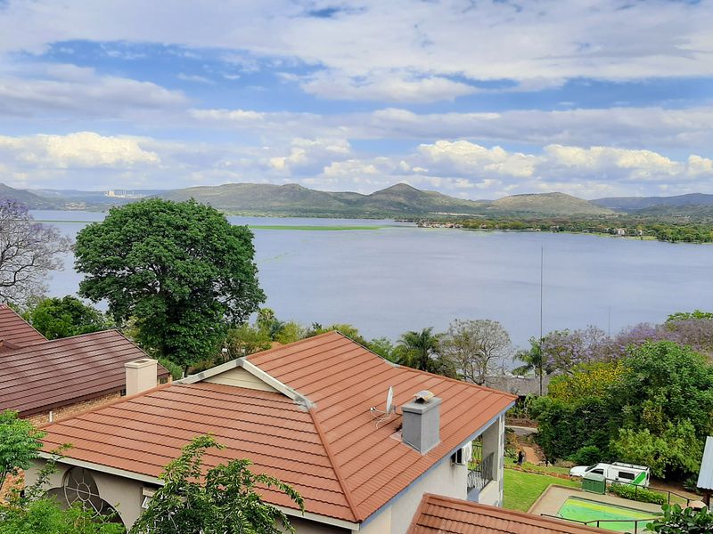Elevated view overlooking a large lake and surrounding hills, showcasing the property's scenic location and roofline.