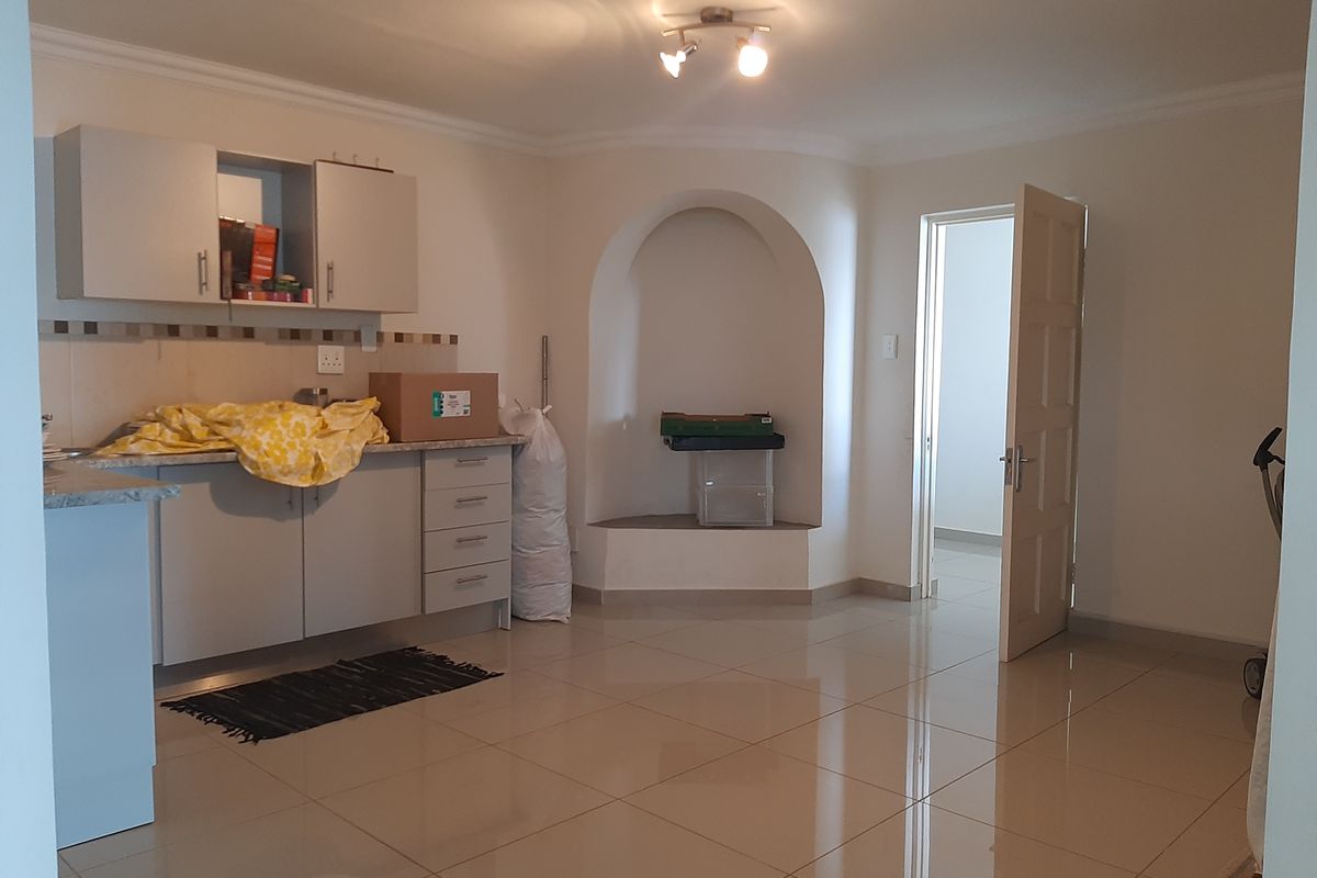 A functional kitchen area featuring built-in cabinetry, granite countertops, and polished tile flooring, complemented by a unique architectural archway alcove.