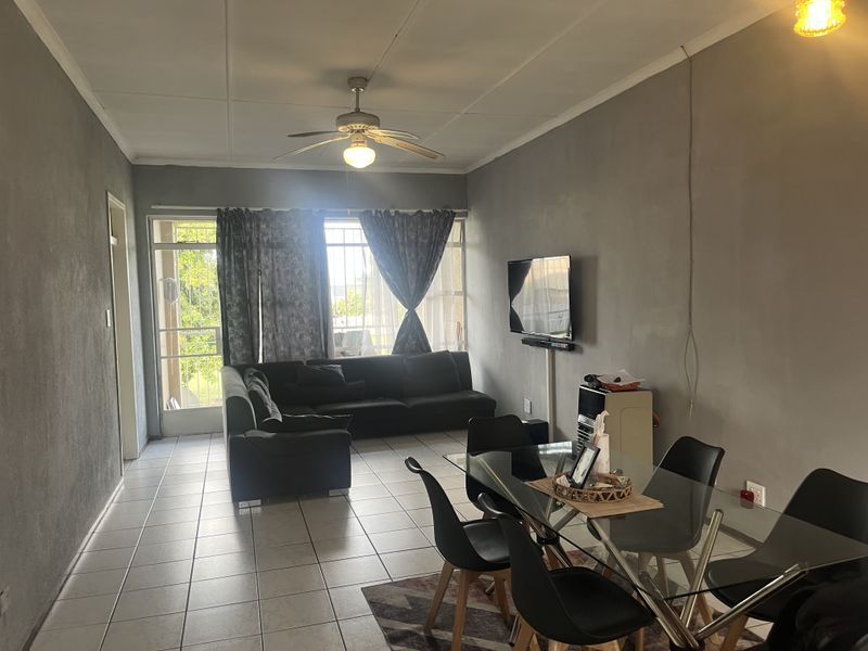 Open-plan living and dining area featuring tiled flooring, a ceiling fan, and access to an outdoor balcony through a sliding glass door.