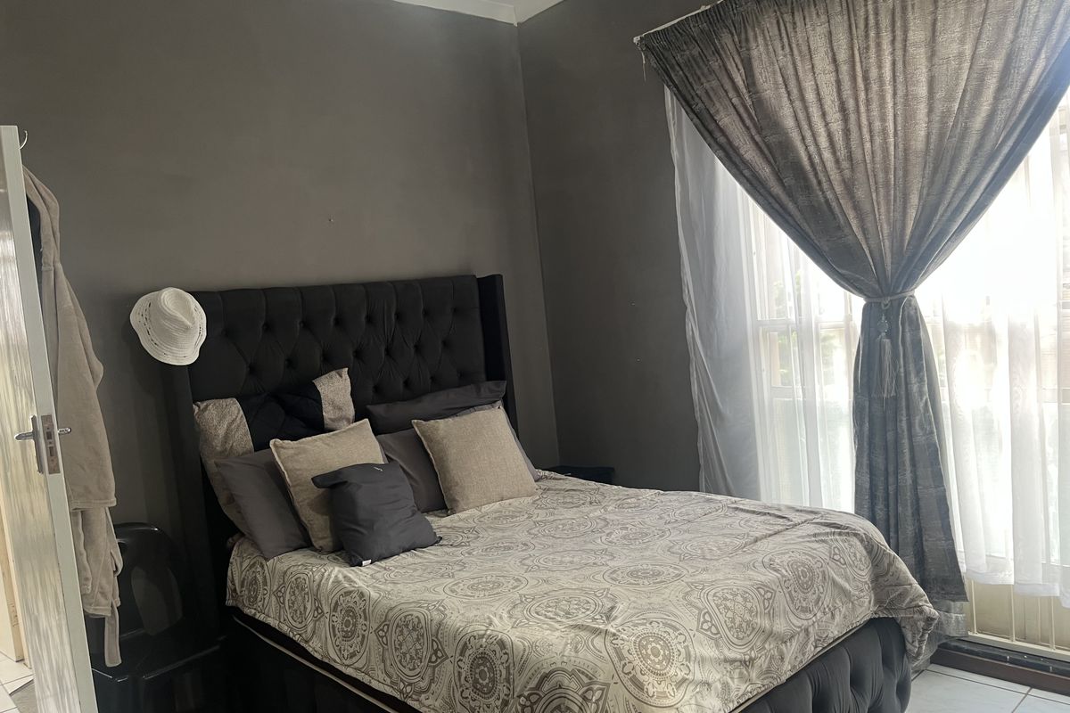 A bedroom featuring tiled flooring and neutral wall tones, offering a functional space with natural light through the window.