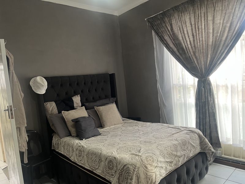 A bedroom featuring tiled flooring and neutral wall tones, offering a functional space with natural light through the window.