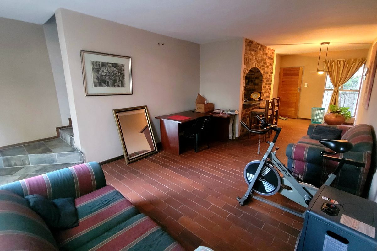 Spacious living area featuring terracotta tiled flooring, a built-in brick fireplace, and direct access to the staircase.