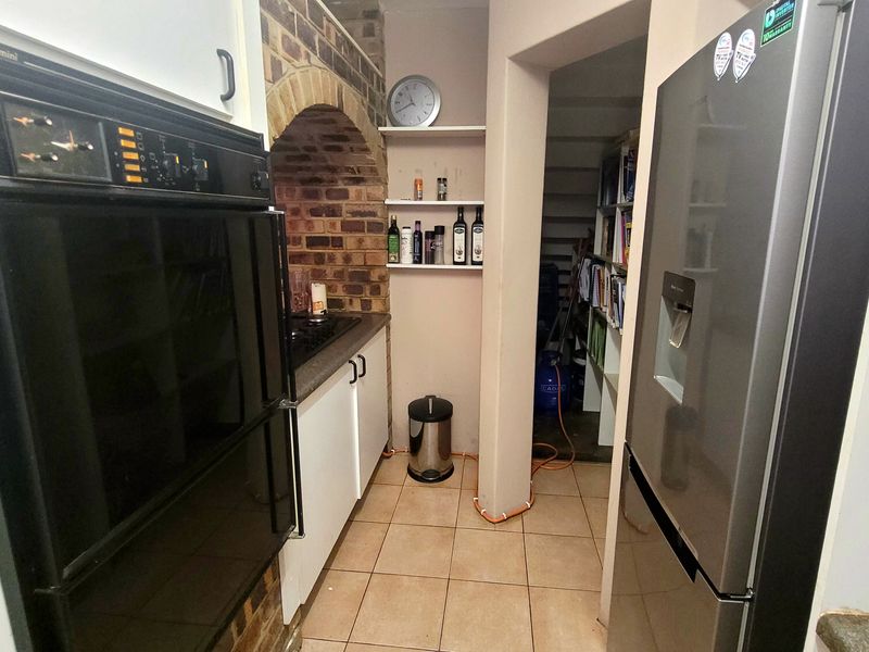 A dated kitchen featuring a brick arch detail, built-in double oven, and tiled flooring, requiring some maintenance to address exposed wiring.