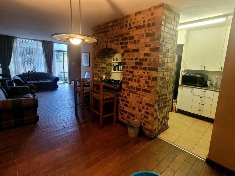 Open-plan living and kitchen area featuring a distinctive brick feature wall, breakfast bar, and tiled flooring throughout.