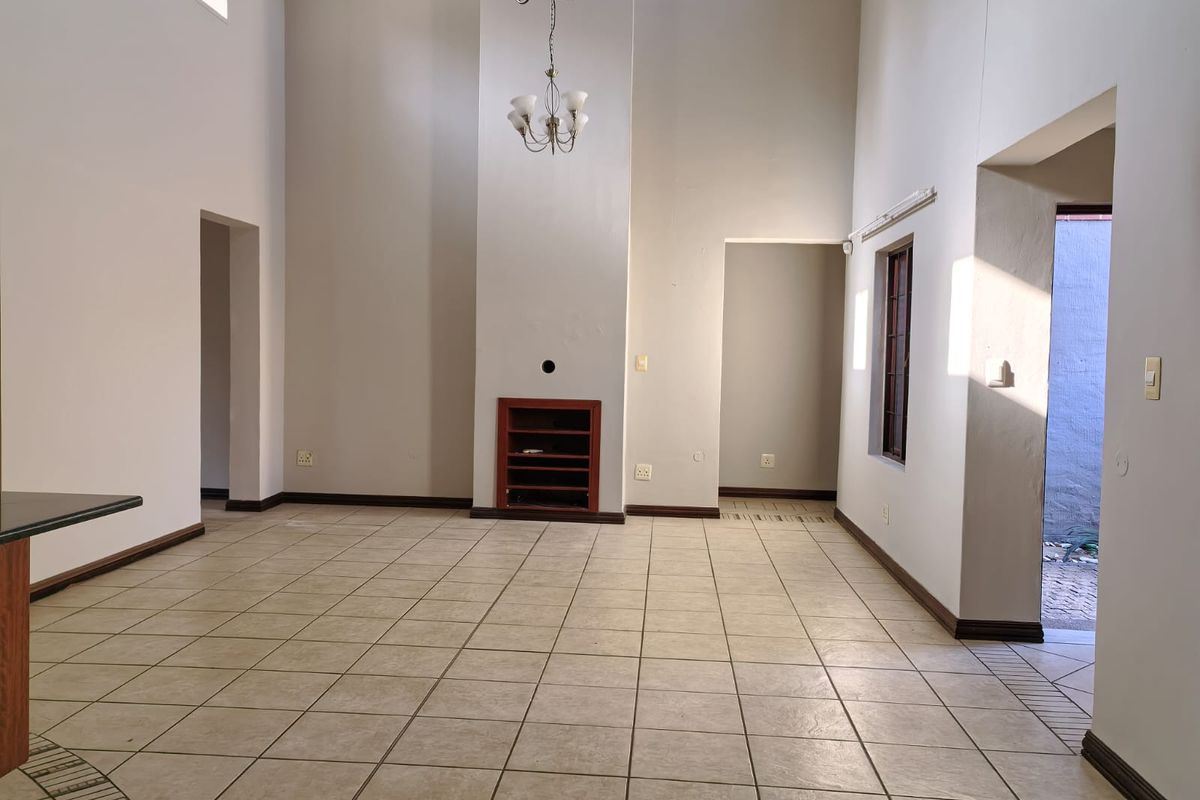 Spacious living area featuring double volume ceilings, tiled flooring, and a built-in fireplace, offering a bright and open layout.