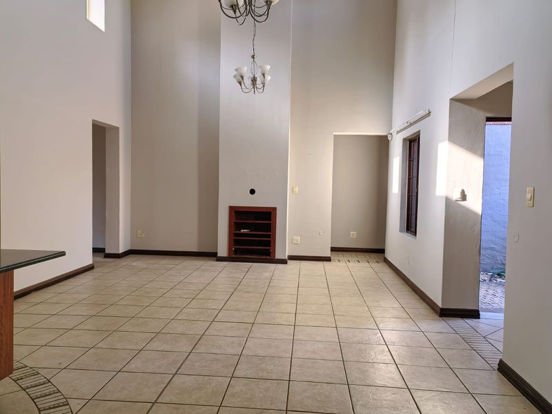 Spacious living area featuring double volume ceilings, tiled flooring, and a built-in fireplace, offering a bright and open layout.