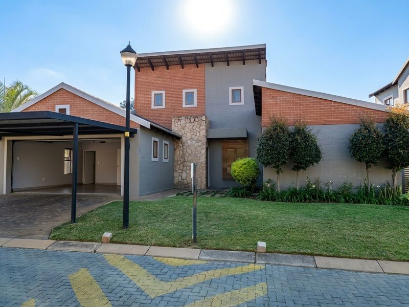 Modern front elevation featuring a combination of brick and stone cladding, a double carport, and a well-maintained front garden.