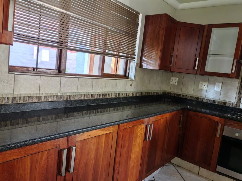 A functional kitchen featuring dark granite countertops, warm-toned wooden cabinetry, a tiled backsplash, and a built-in oven.