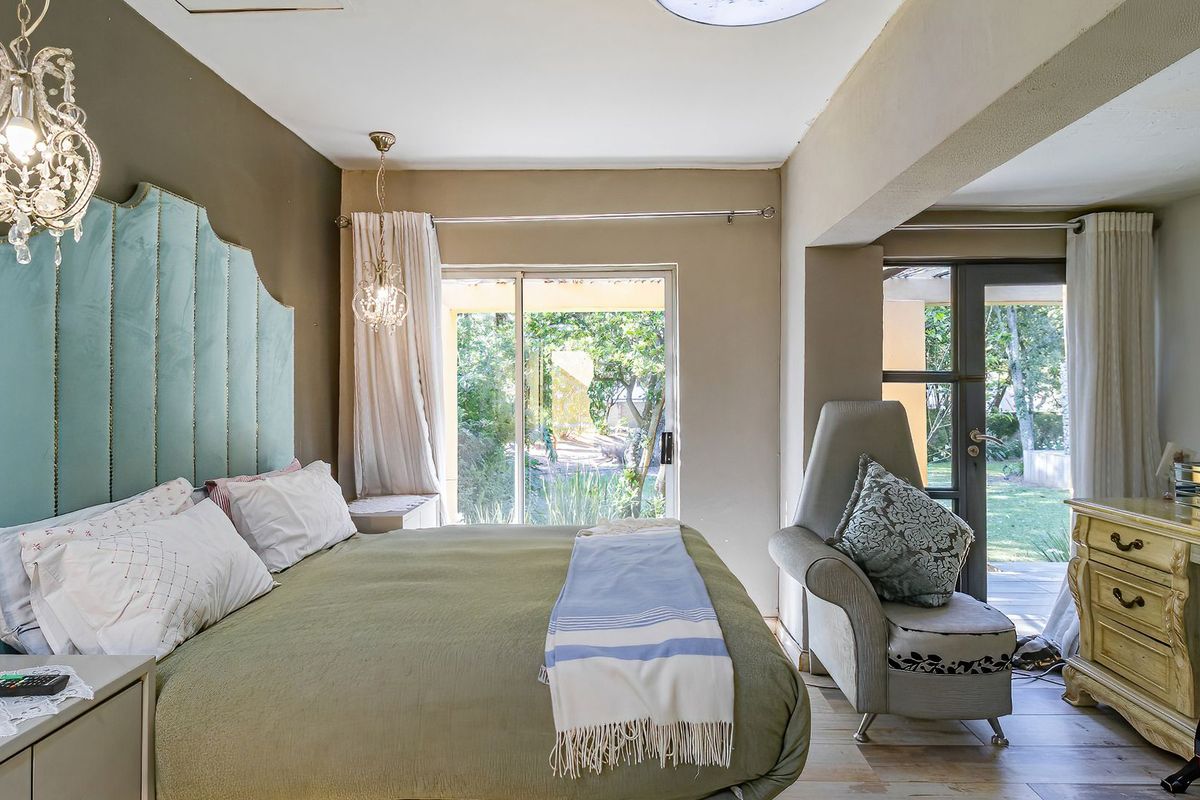 A well-lit bedroom featuring tiled flooring, a sliding glass door providing garden access, and a secondary glass door leading to an outdoor area.