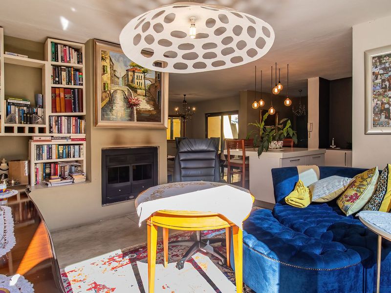 An open-plan living area featuring a built-in fireplace, integrated shelving, and a kitchen island with pendant lighting, creating a cohesive and functional living space.